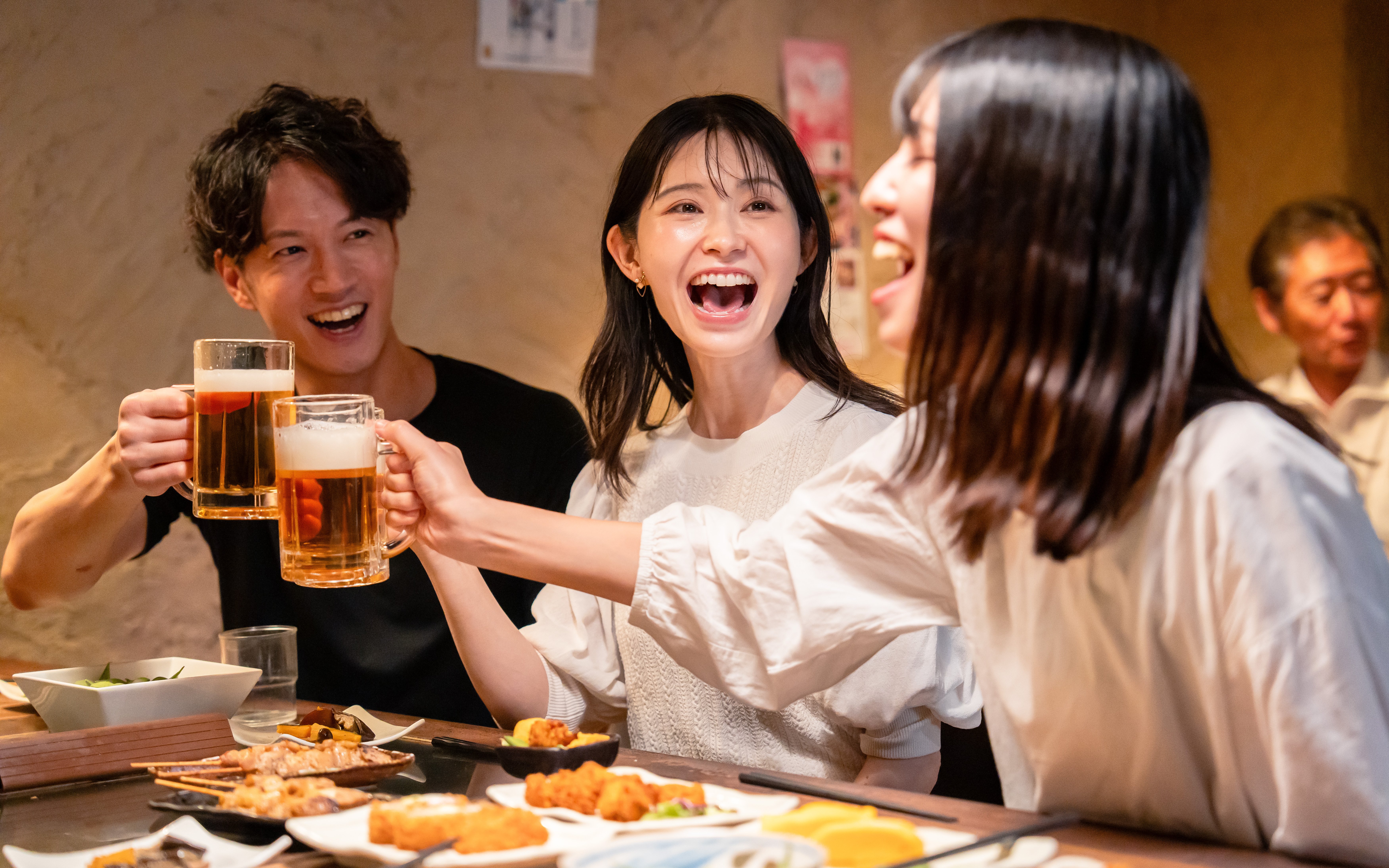 Young adults enjoying drinks and food at a Japanese izakaya.