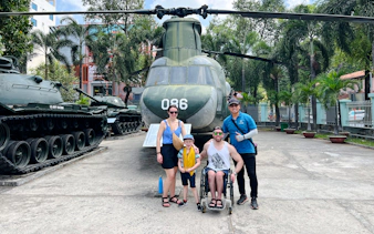 Family posing in front of a military helicopter at a museum in Ho Chi Minh City.