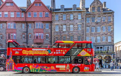 Edinburgh hop-on hop-off bus in front of historic buildings on a city street.
