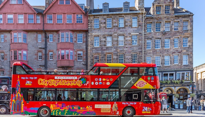Edinburgh hop-on hop-off bus passing by historic city landmarks.