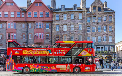 Edinburgh hop-on hop-off bus in front of historic buildings on a city street.