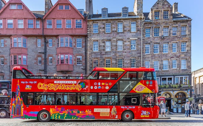 Edinburgh hop-on hop-off bus in front of historic buildings on a city street.