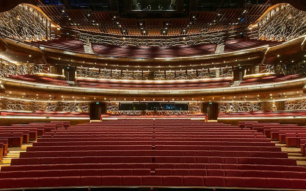 Interior view of Dubai Opera auditorium with red seating and ornate balconies.