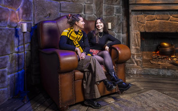 Two people sitting in a cozy, stone-walled room at Harry Potter™: The Exhibition.
