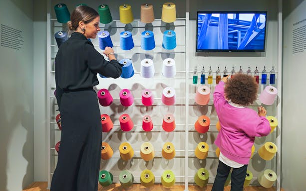 Visitors exploring colorful yarn display at Porto Fashion and Fabric Museum.