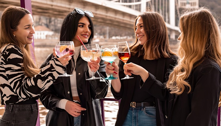 Friends enjoying cocktails on a Budapest cruise with cityscape views.