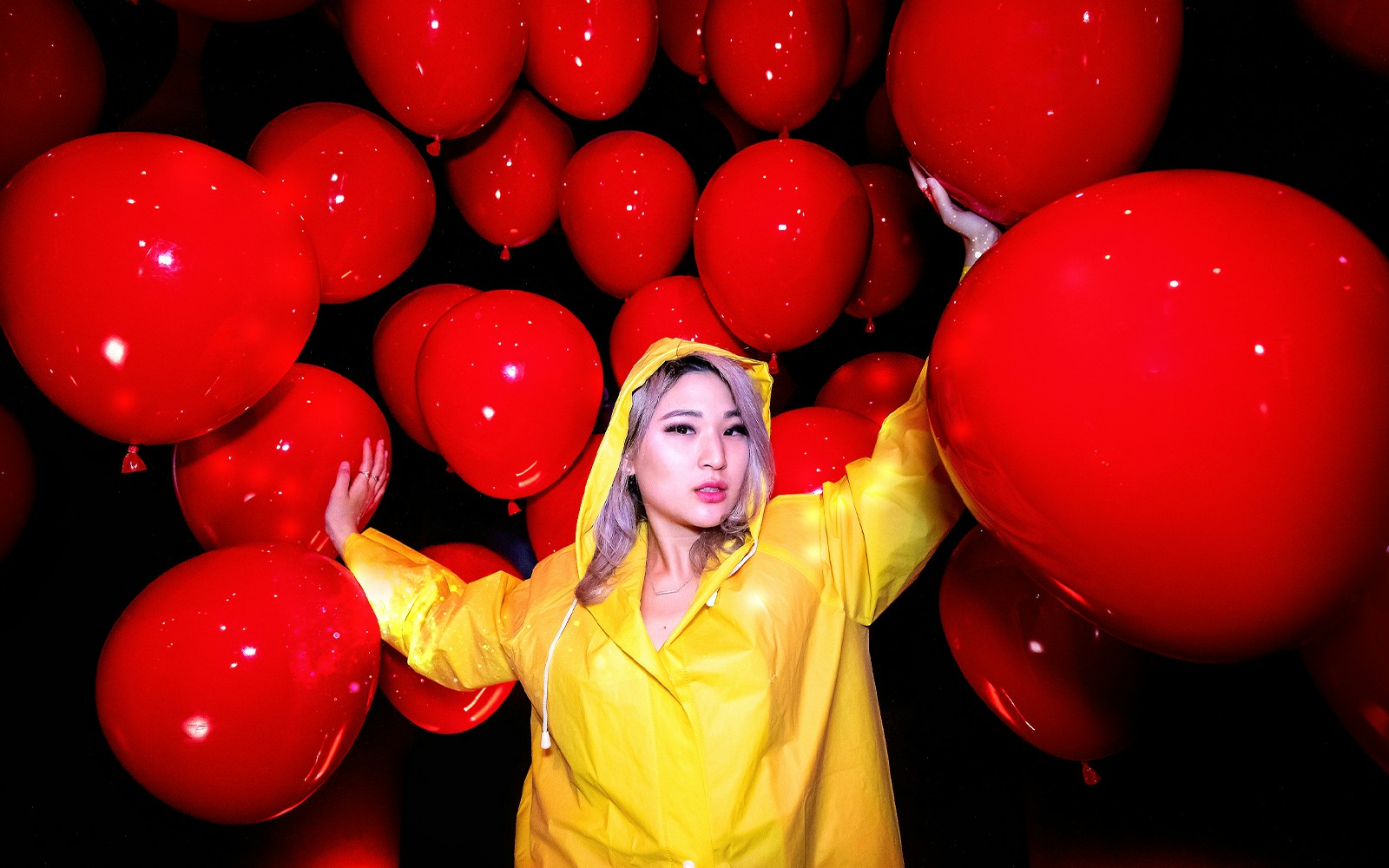 Person in yellow raincoat surrounded by red balloons at Madame Tussauds Hollywood.