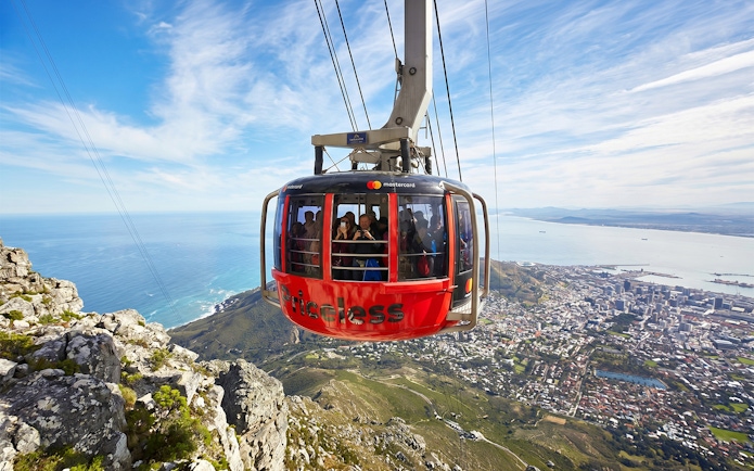 Cable car ascending Table Mountain with Cape Town cityscape below.