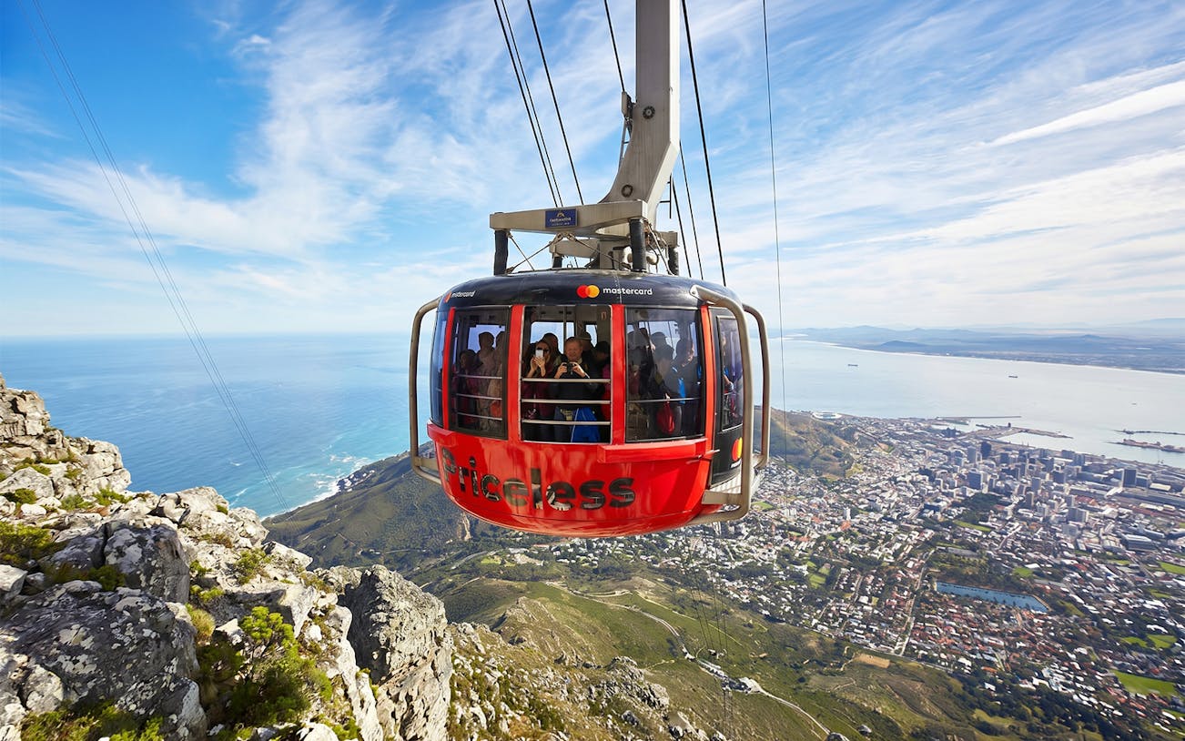 Cable car ascending Table Mountain with Cape Town cityscape below.