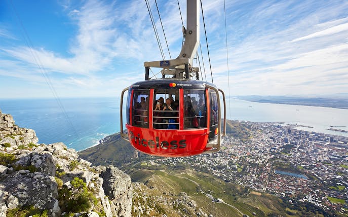 Cable car ascending Table Mountain with Cape Town cityscape below.