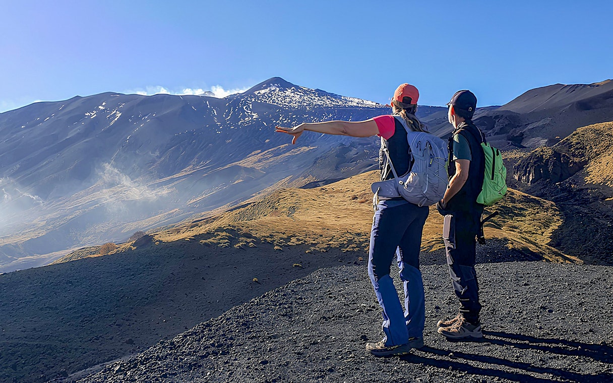 Hikers pointing towards Mount Etna during an afternoon guided tour.
