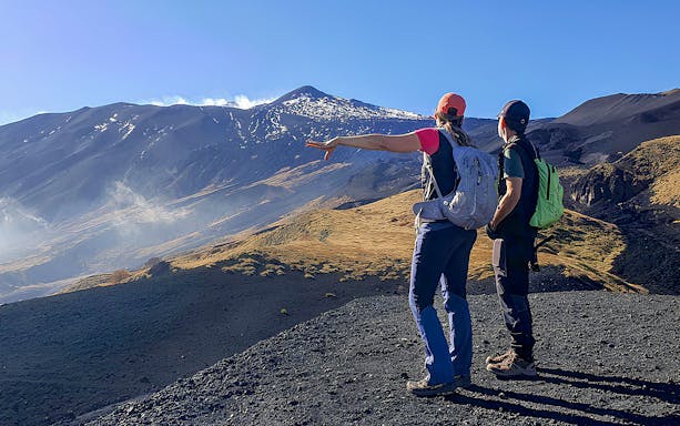 Hikers pointing towards Mount Etna during an afternoon guided tour.