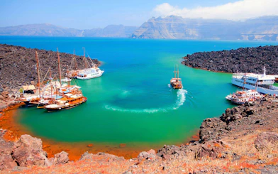 Boats anchored near volcanic island during Santorini Volcano Boat Tour.