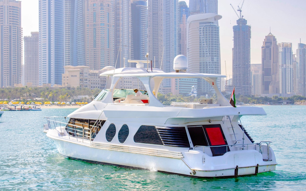 Luxury yacht cruising in Dubai Marina with skyscrapers in the background.
