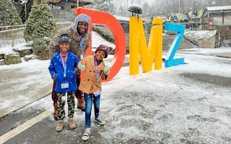 Family posing by colorful DMZ sign in snowy Korean Demilitarized Zone.