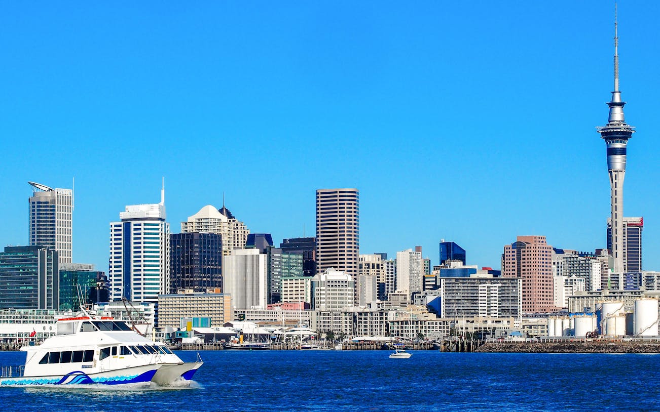 Cruise boat on Auckland Harbour with city skyline and Sky Tower in view.