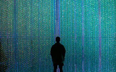 Visitor at teamLab Borderless Museum in Tokyo surrounded by colorful digital art installation.