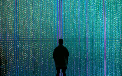 Visitor at teamLab Borderless Museum in Tokyo surrounded by colorful digital art installation.