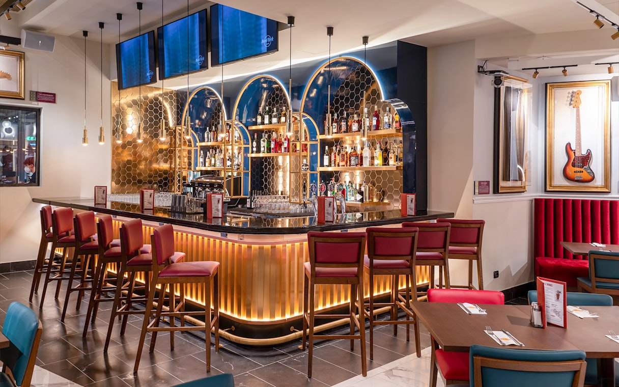 Hard Rock Cafe Milan bar area with seating and guitar decor.