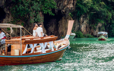 Longtail boat sailing near limestone cliffs in Krabi, Thailand.