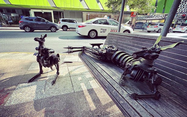 Metal kangaroo sculptures on a bench in Brisbane city street.