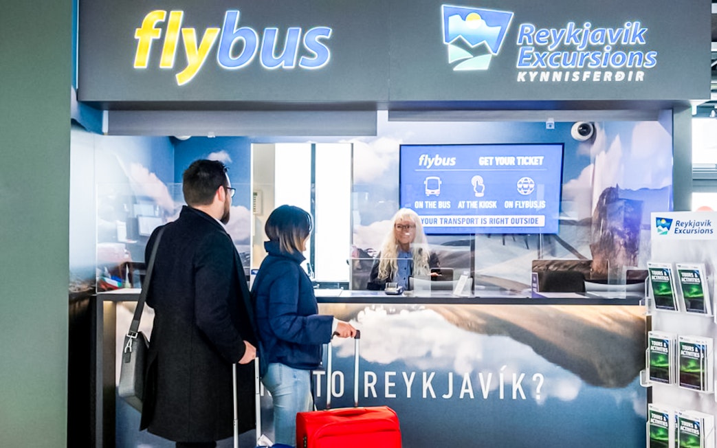 Flybus ticket counter at Reykjavik Keflavik Airport with travelers purchasing tickets.