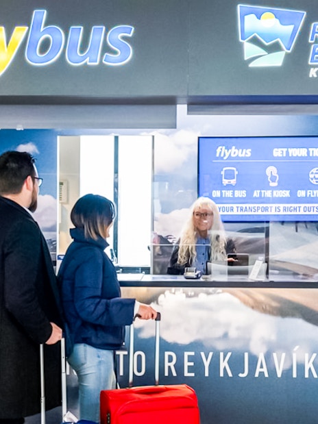 Flybus ticket counter at Reykjavik Keflavik Airport with travelers purchasing tickets.