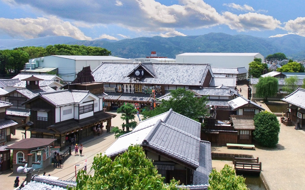 TOEI Kyoto Studio Park traditional buildings with mountain backdrop.
