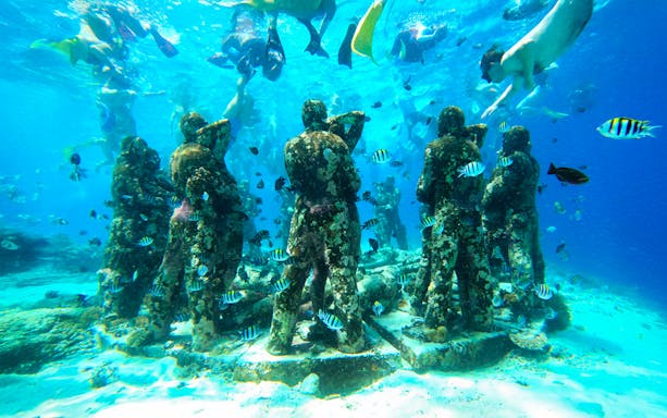 Underwater statues surrounded by fish during snorkeling trip to Northern Coast Gili Islands.