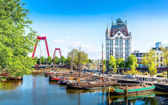 Rotterdam canal with historic boats and Witte Huis building in the background.