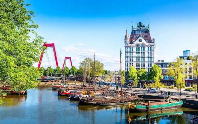 Rotterdam canal with historic boats and Witte Huis building in the background.