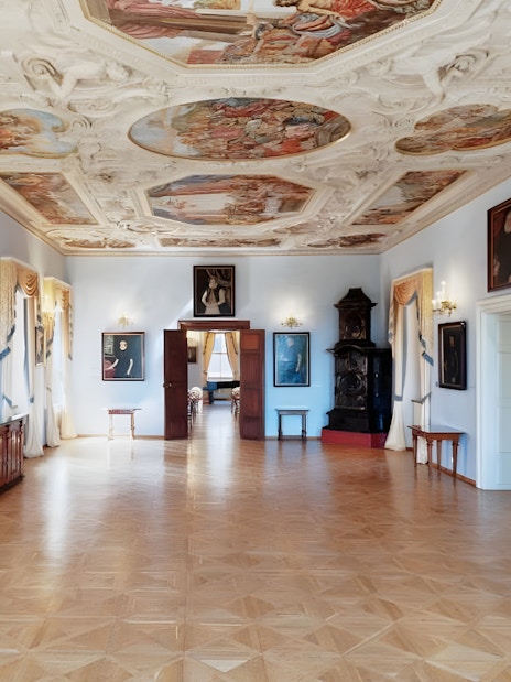 Lobkowicz Palace Museum interior with ornate ceiling and historical paintings, Prague.
