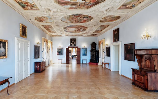 Lobkowicz Palace Museum interior with ornate ceiling and historical paintings, Prague.