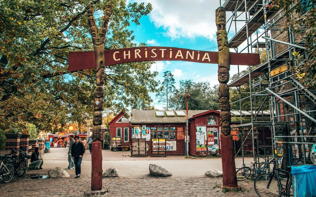Entrance to Freetown Christiania in Copenhagen with colorful buildings and people exploring.