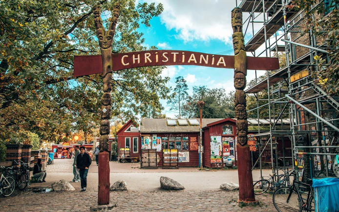 Entrance to Freetown Christiania in Copenhagen with colorful buildings and people exploring.