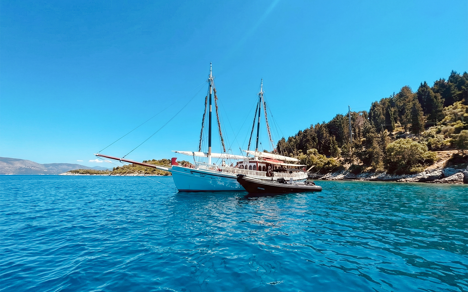 Sailing boat on a coastal cruise near Corfu, Greece, with lush shoreline.