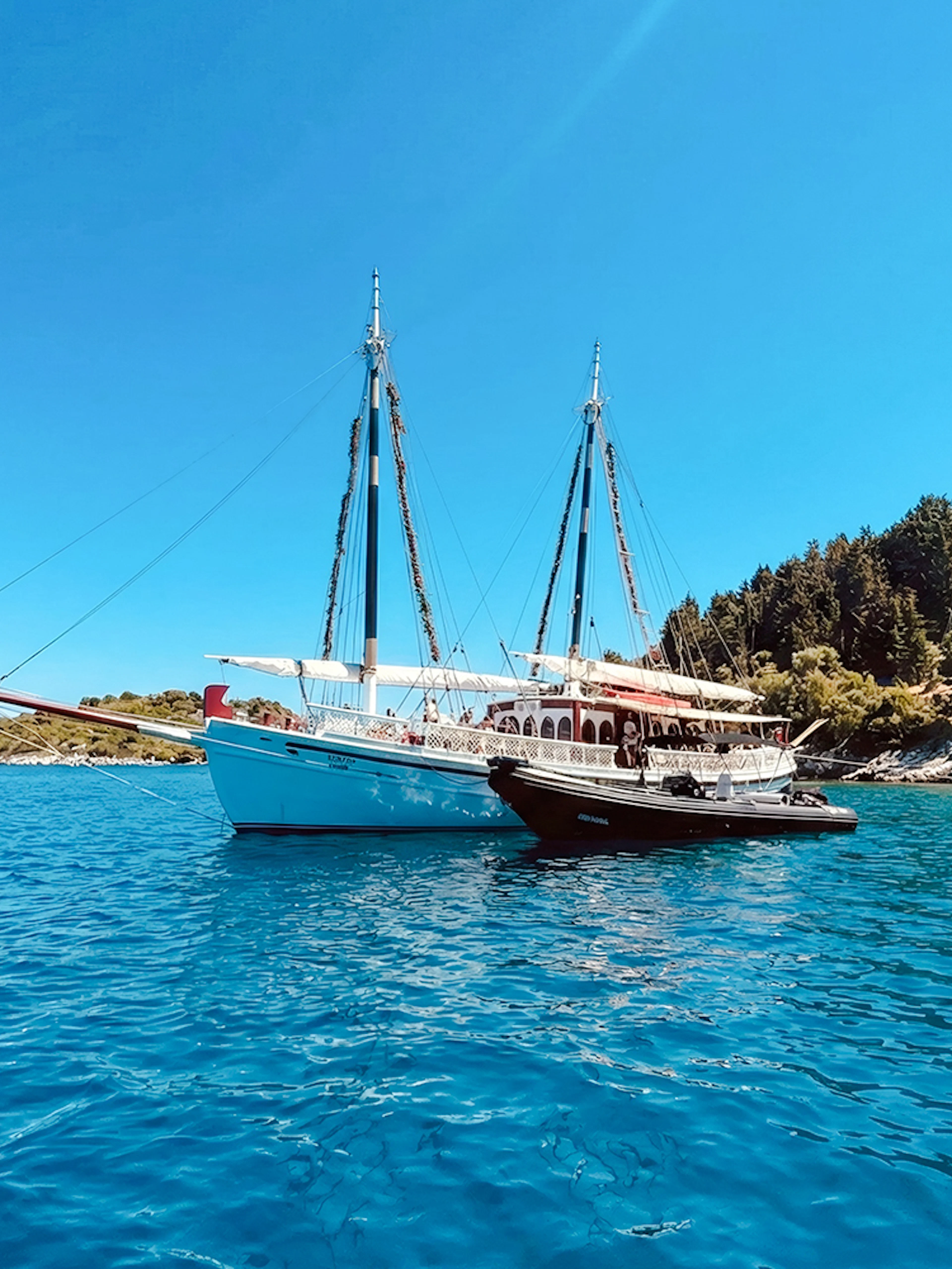 Sailing boat on a coastal cruise near Corfu, Greece, with lush shoreline.