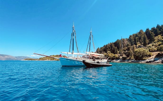 Sailing boat on a coastal cruise near Corfu, Greece, with lush shoreline.
