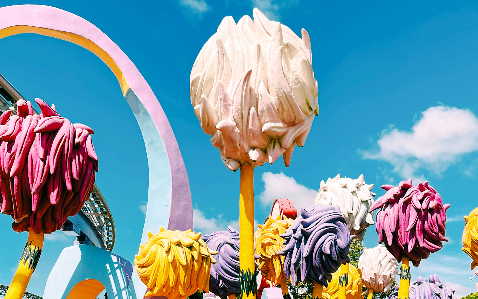 Colorful Seussian trees under a blue sky at a theme park.