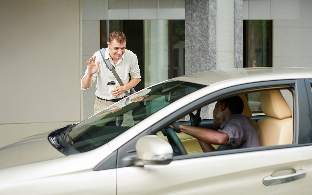 Man greeting driver in parked car outside building.