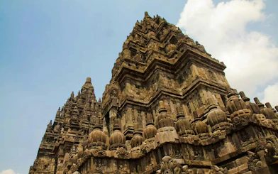 Prambanan Temple's intricate stone carvings and towering spires under a clear sky.