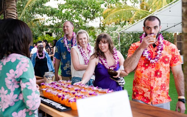 Guests receiving welcome drinks at Mauka Warriors Luau entrance.