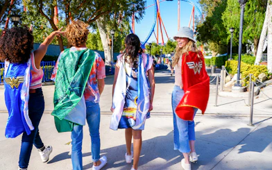 Visitors wearing superhero capes walking towards SCREAM ride at Six Flags Magic Mountain.