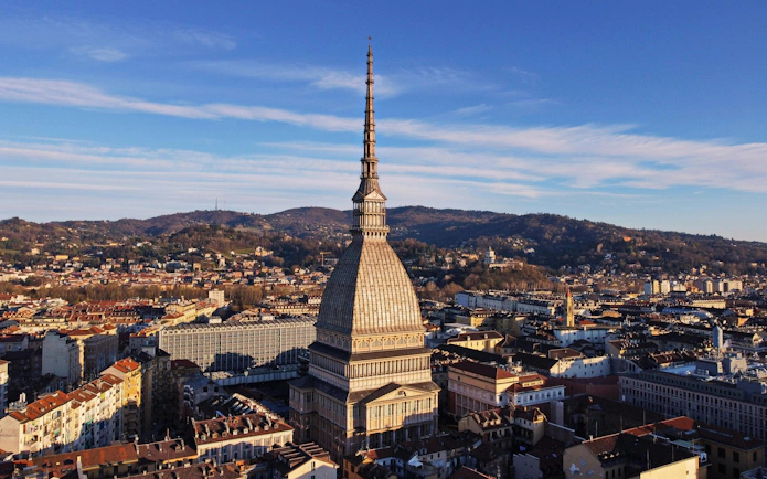 Mole Antonelliana in Turin, home to the National Museum of Cinema, with cityscape and hills.