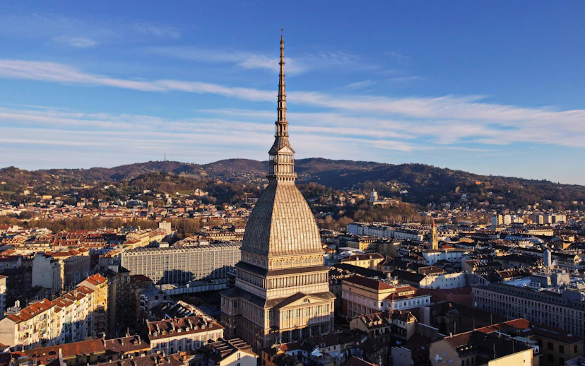 Mole Antonelliana in Turin, home to the National Museum of Cinema, with cityscape and hills.