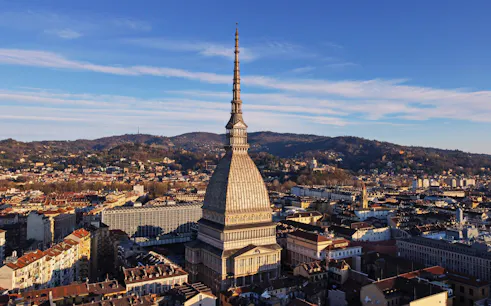 Mole Antonelliana in Turin, home to the National Museum of Cinema, with cityscape and hills.