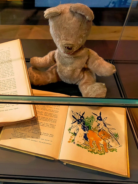 Burned toy and children's books displayed at D-Day Normandy museum exhibit.