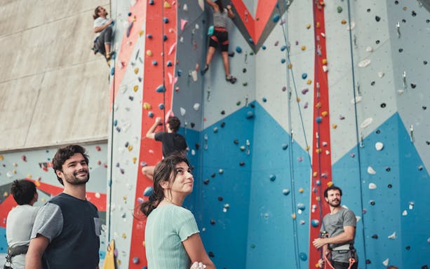 Climbers scaling a colorful indoor climbing wall during a bridge climbing experience.