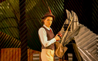 Performer in costume with a metal horse prop during "The Elixir of Love" opera.