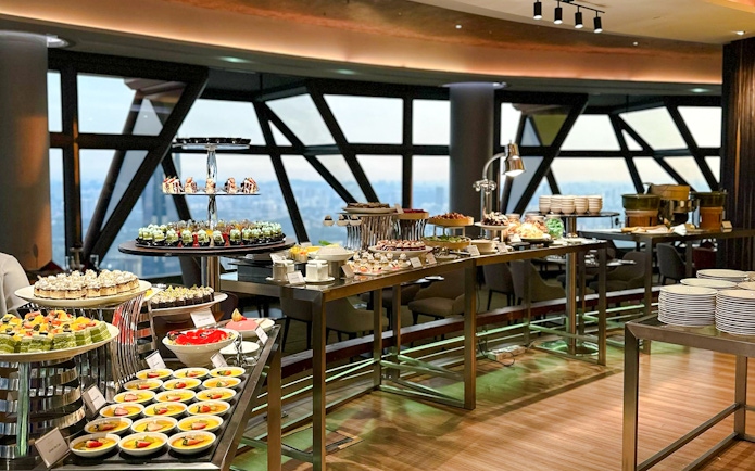 Lunch buffet spread at ORBIT Revolving Dining, KL Tower, featuring assorted desserts and city view.